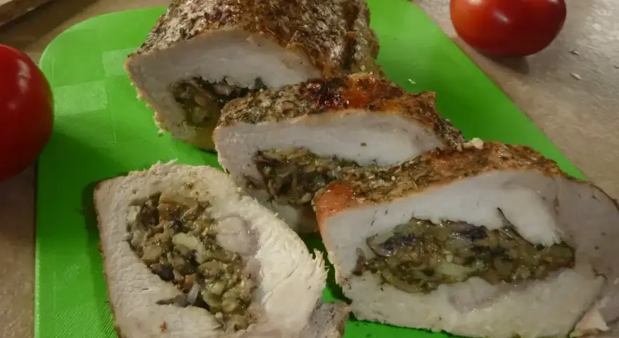 Pyszny kotlet husarski, pieczony z ziołami i nadzieniem grzybowym, pokrojony na desce.